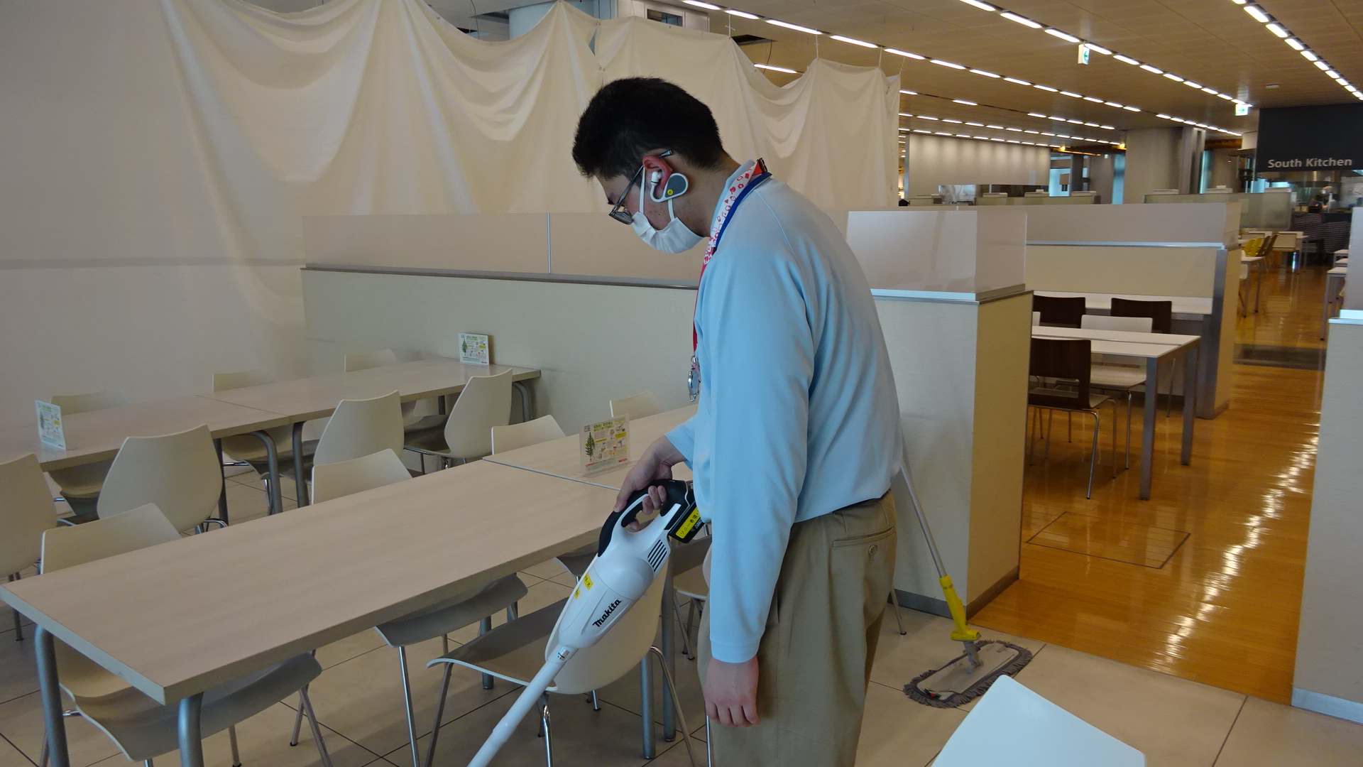 スタッフが「NYSNO-100」でサポーターと会話しながら食堂の清掃業務を行う画像